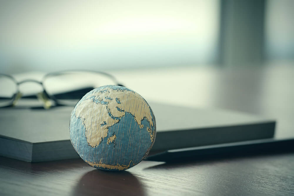 A photo of a globe of the earth placed on a wooden table.