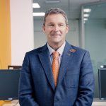 A portrait image of Nunzio Quacquarelli, Founder and President of QS, wearing a blue suit with an orange tie.