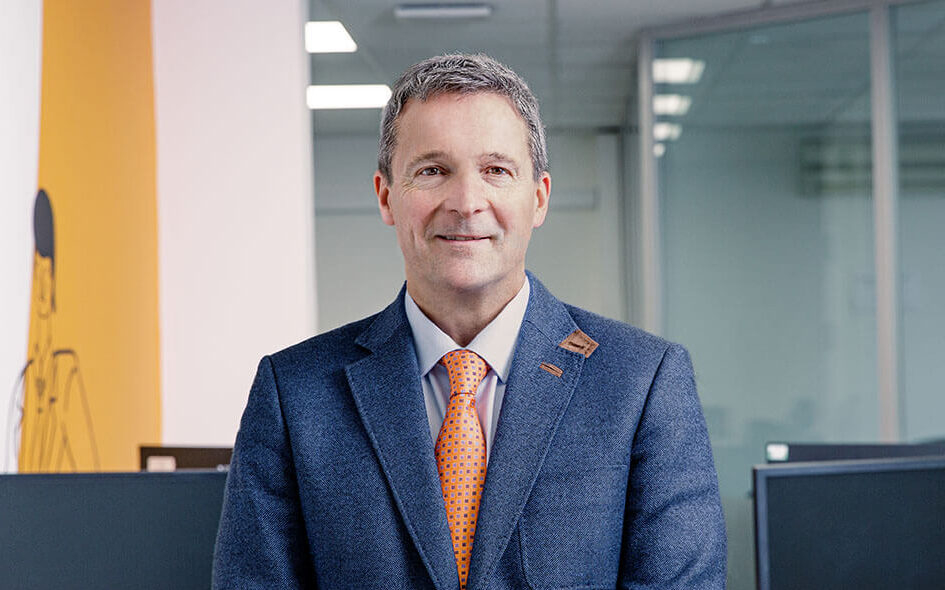 A portrait image of Nunzio Quacquarelli, Founder and President of QS, wearing a blue suit with an orange tie.