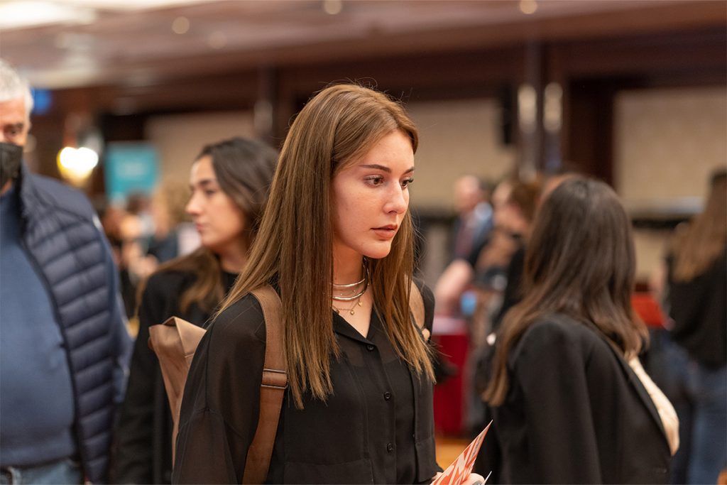 A photo of a student in a conference hall holding a pamphlet.