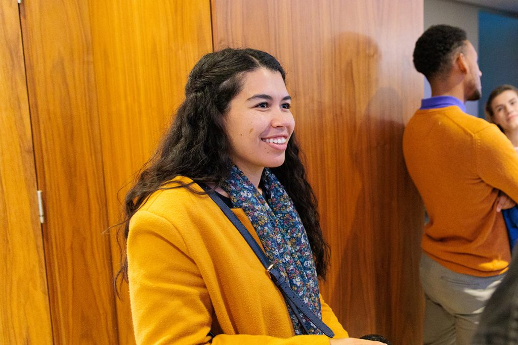 A photo of a student dressed in a yellow coat smiling.
