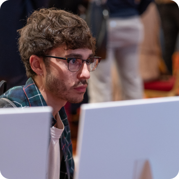 A photo of a man in glasses staring at a computer screen.