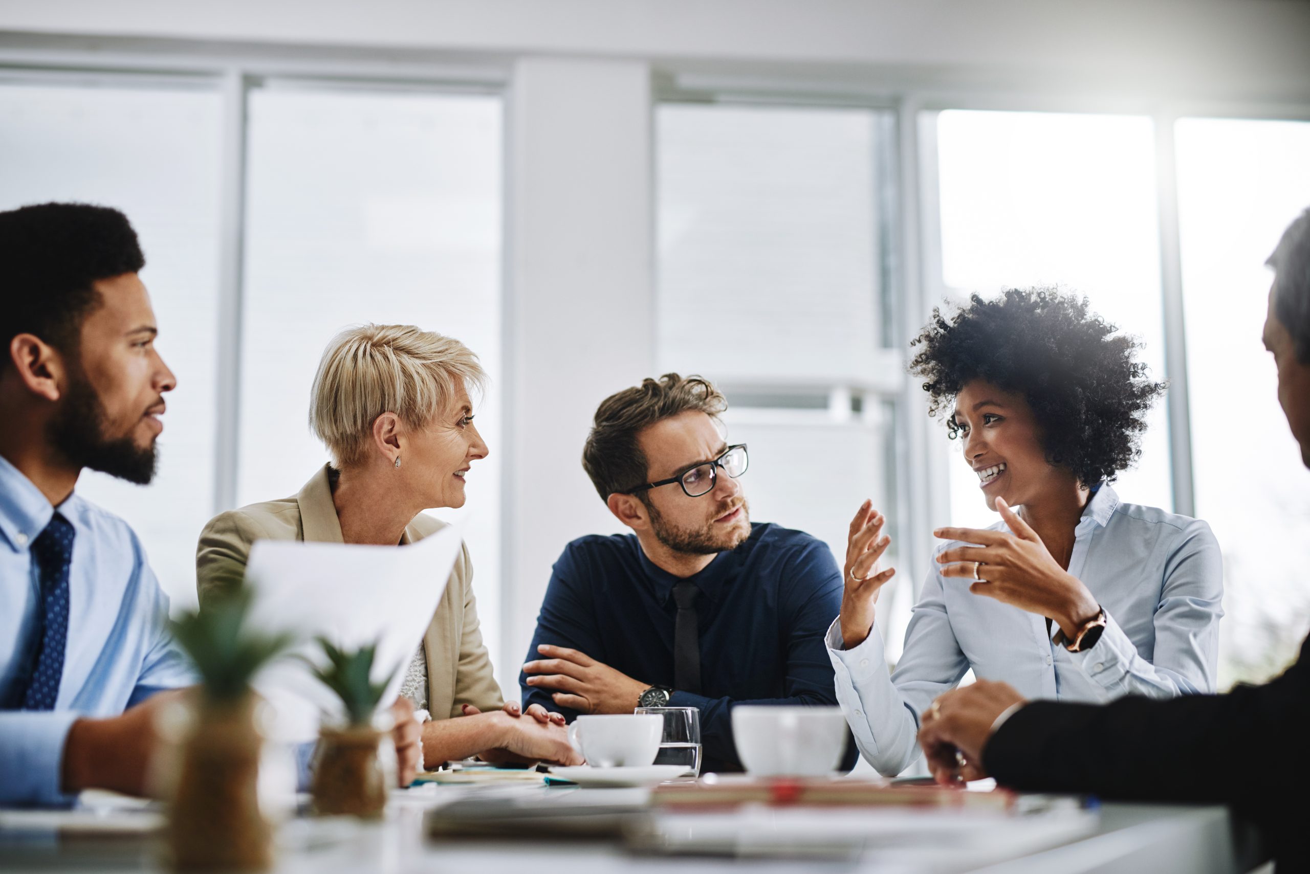 5 employees are having a sit-down meeting in an office.