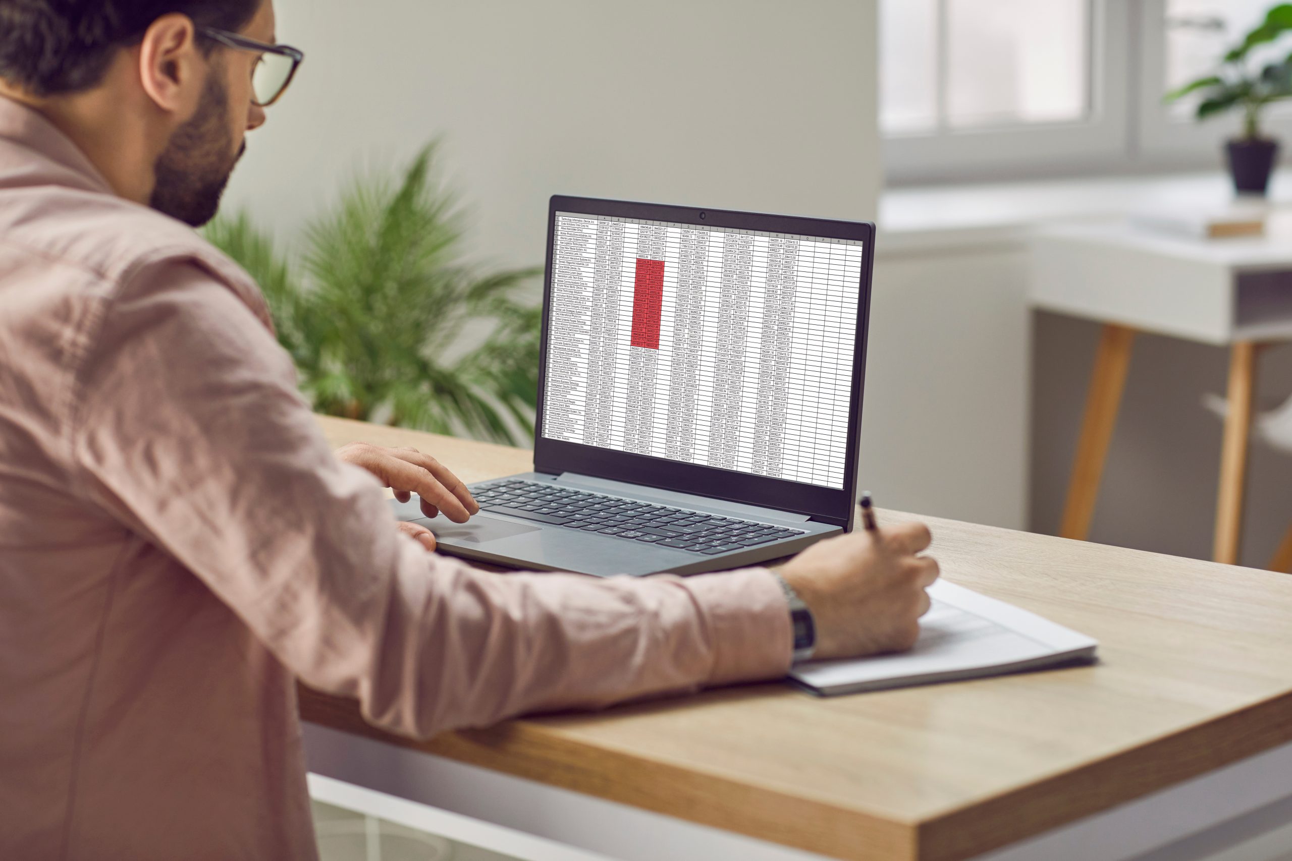 A photo of a man in an office doing work on a laptop.