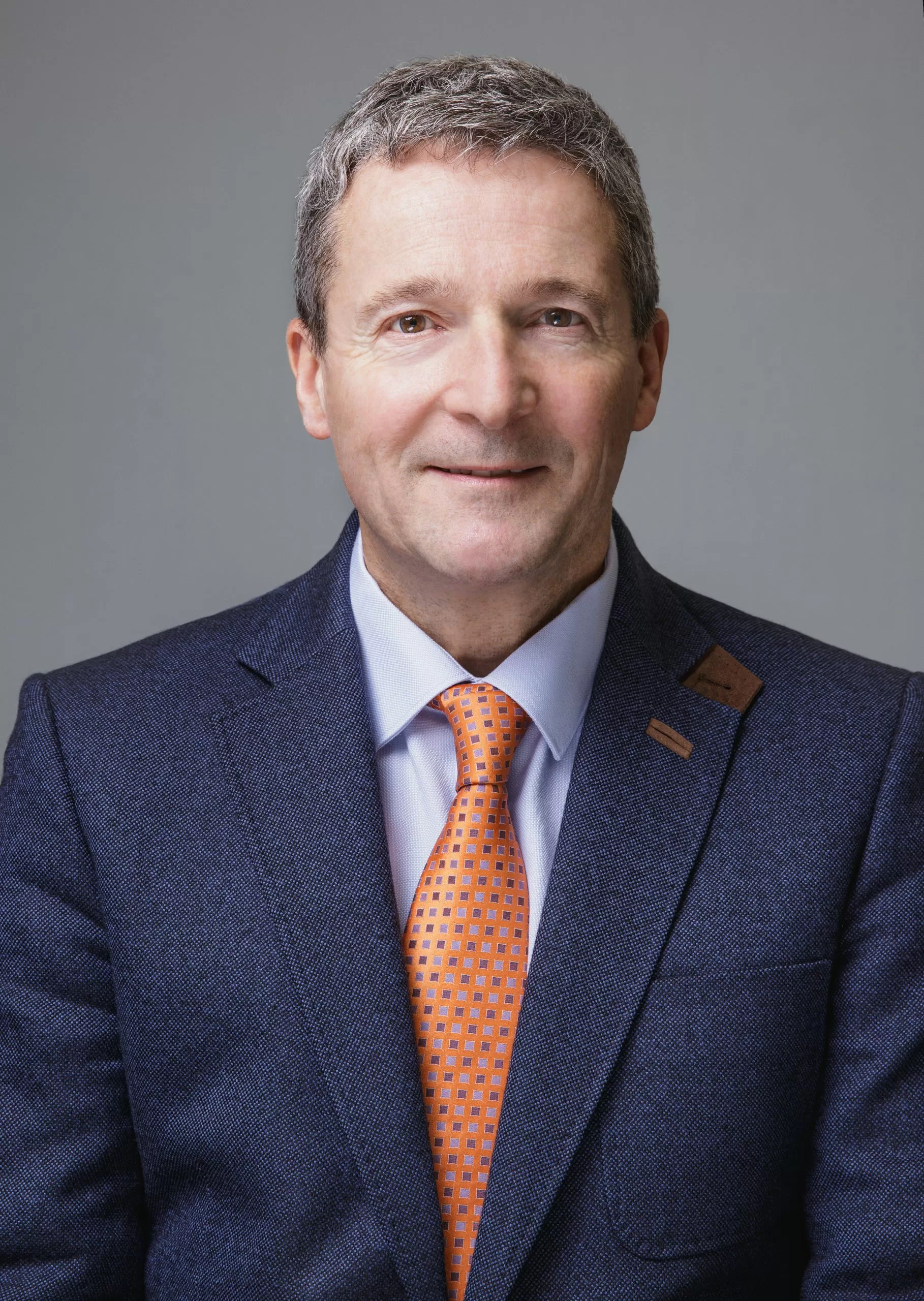 A portrait image of Nunzio Quacquarelli, Founder and President of QS, wearing a blue suit with an orange tie.