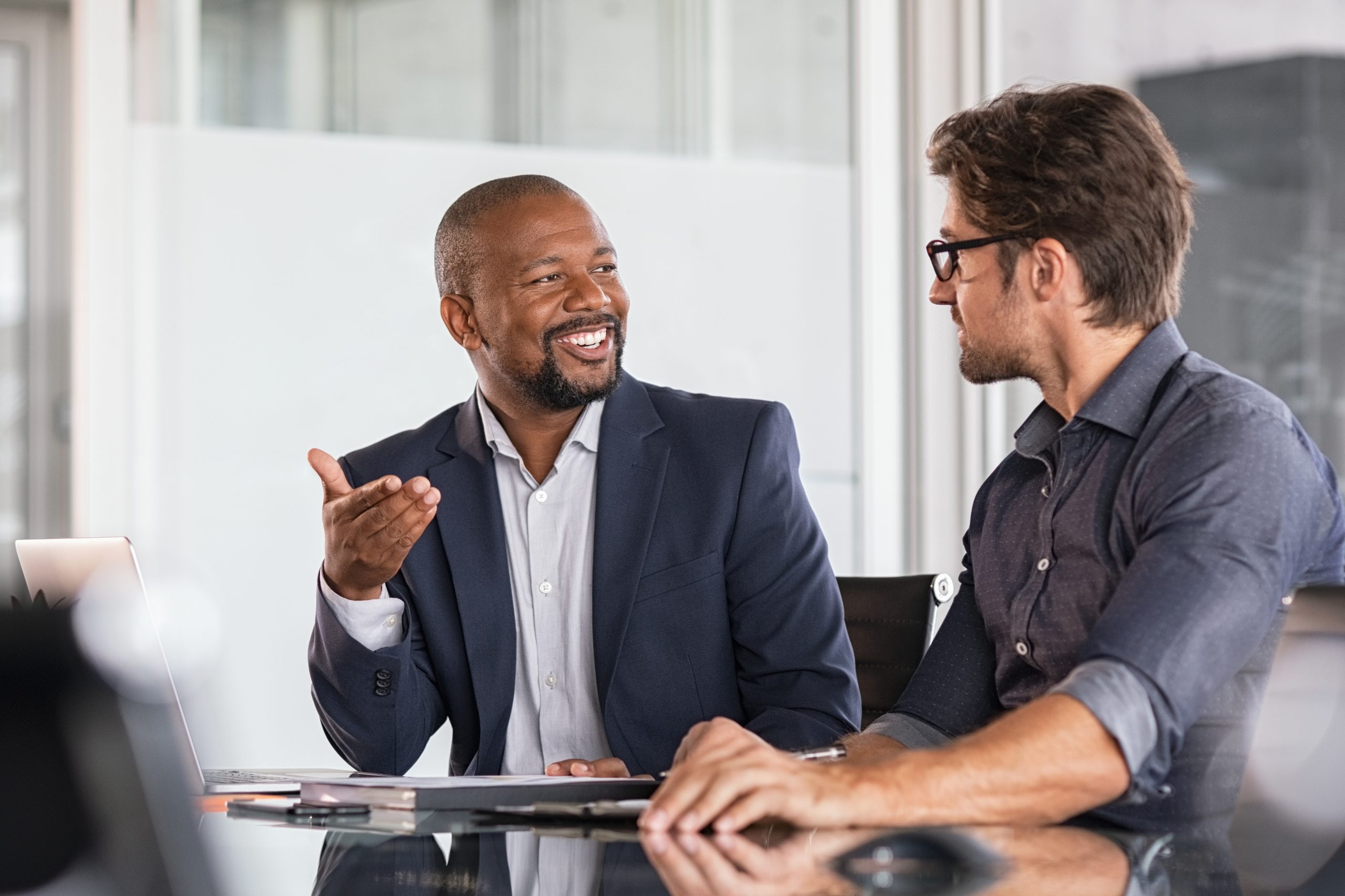 Two colleagues have a conversation whilst sitting at a table.