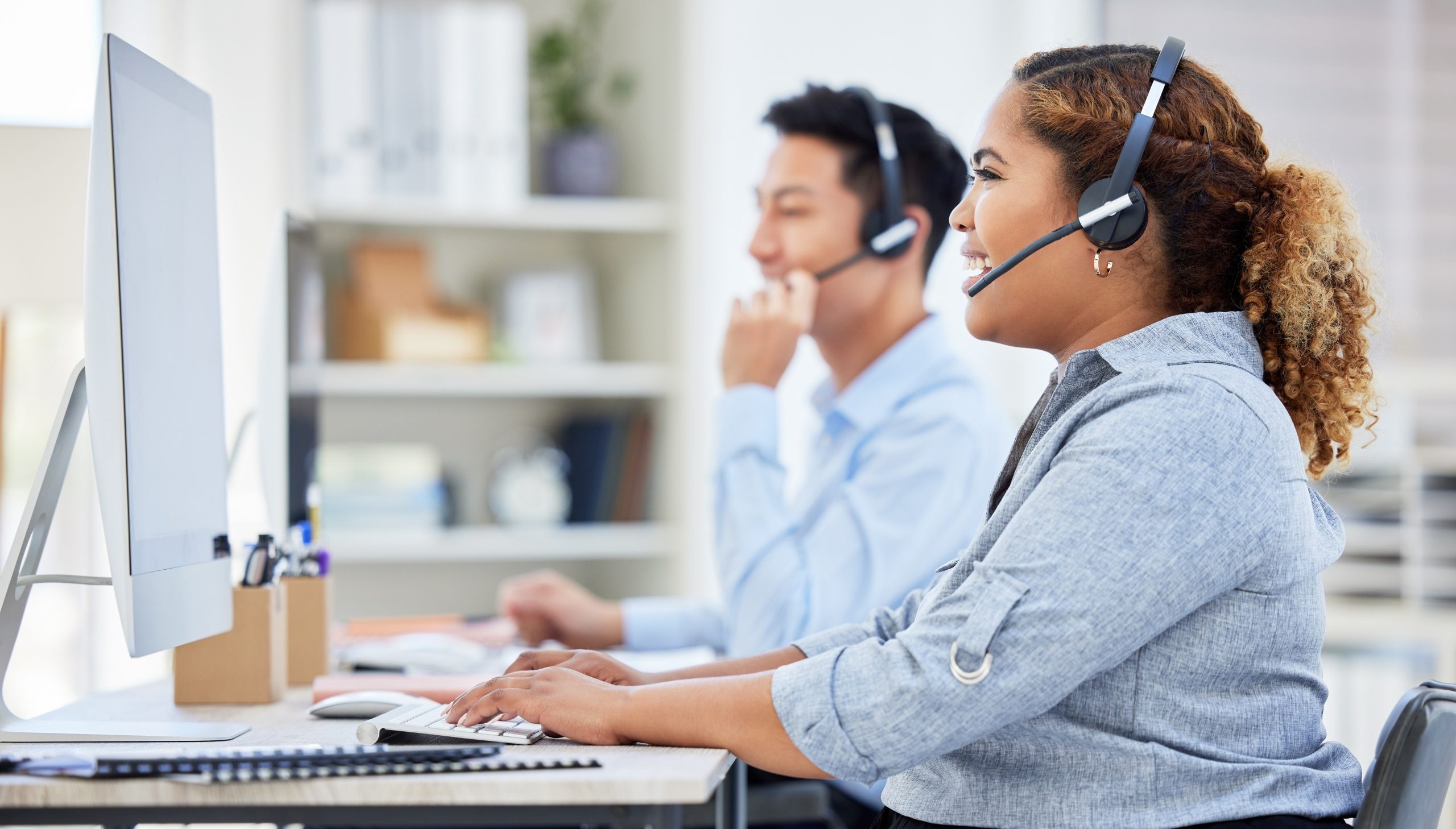 Happy, confident and smiling call centre agent talking on a headset while working on computer in an office. Saleswoman or consultant operating a help desk for customer care and service support