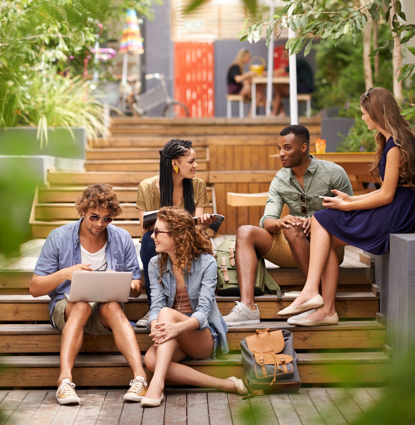 A group of students are sitting outside on their campus’ garden steps and having a friendly discussion.