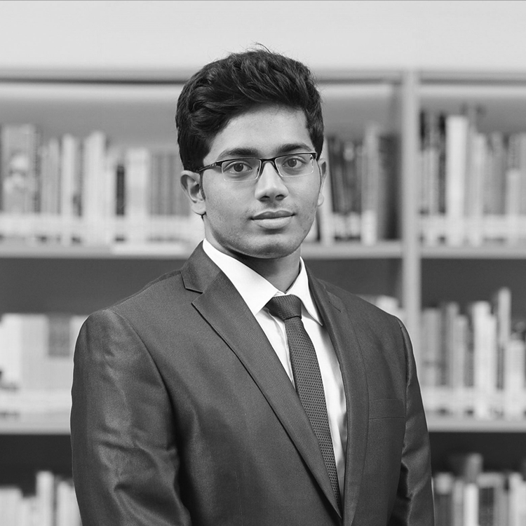 A black and white portrait of Kuldeep Reddy, Senior Operations Manager at QS, in front of a bookcase wearing glasses and a dark suit.