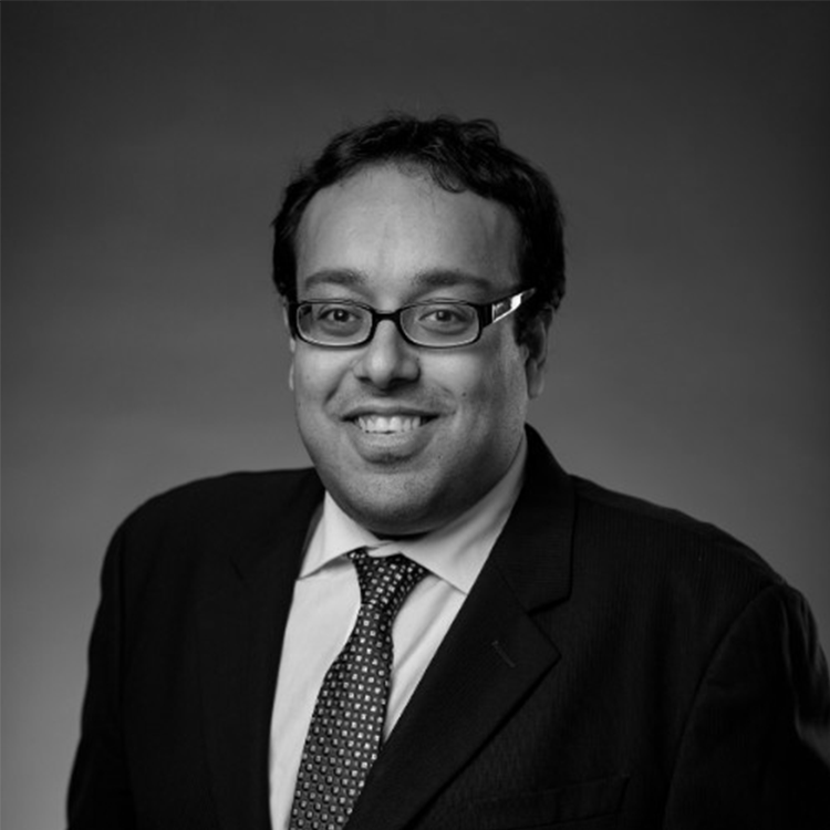 A black and white portrait of Zaeem Siddiqui, Data and Insights Manager for QS. He’s wearing rectangular glasses and a suit.
