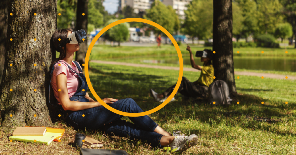 A student sat under a tree with a VR headset on