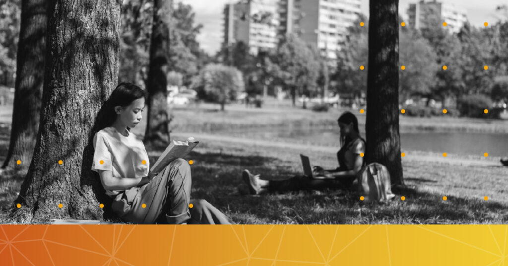 Two students under a tree on a university campus.