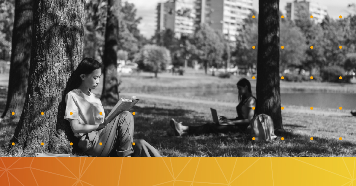 Two students under a tree on a university campus.